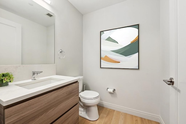 bathroom with hardwood / wood-style flooring, vanity, and toilet