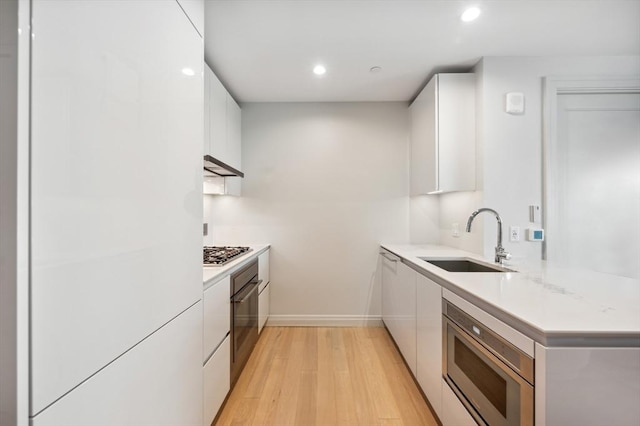 kitchen with sink, white cabinetry, light hardwood / wood-style flooring, oven, and stainless steel gas stovetop