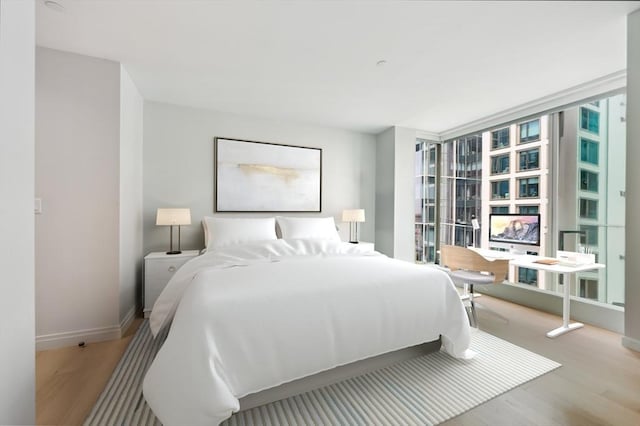 bedroom with floor to ceiling windows and light hardwood / wood-style flooring