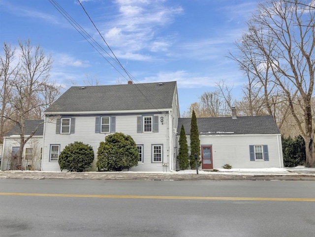 colonial inspired home with roof with shingles and a chimney