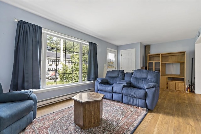 living room with wood-type flooring, a wealth of natural light, and a baseboard heating unit