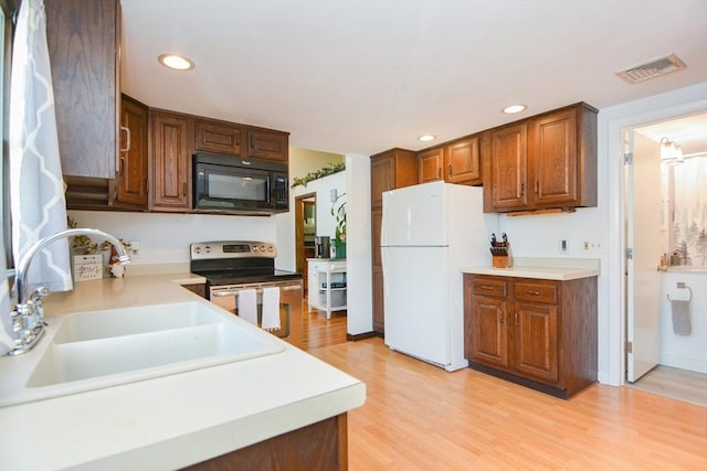 133 E Main St, Norton, MA 02766 - kitchen with black microwave, freestanding refrigerator, stainless steel range with electric stovetop, a sink, and light wood-style floors