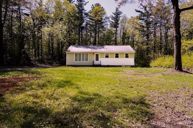 ranch-style house with a front yard and a forest view
