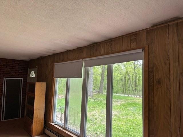 doorway to outside with a textured ceiling and wood walls