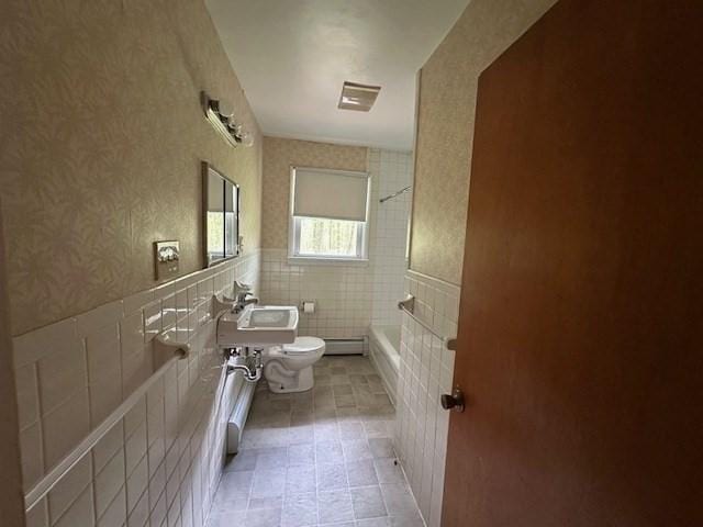 bathroom with toilet, baseboard heating, wallpapered walls, tile walls, and bathing tub / shower combination