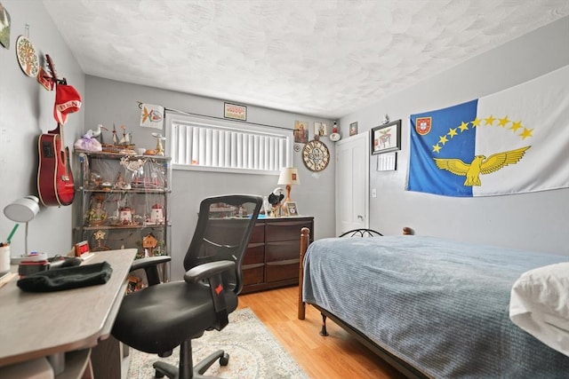 bedroom featuring a textured ceiling and light hardwood / wood-style flooring