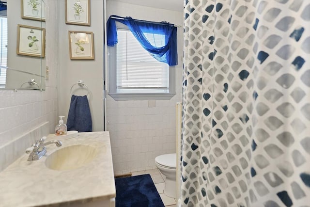 bathroom with tile walls, a wealth of natural light, tile patterned floors, and toilet