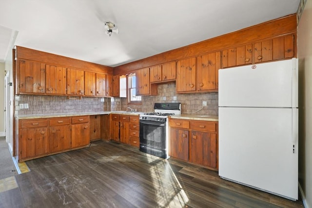 kitchen with tasteful backsplash, gas range, white fridge, and dark hardwood / wood-style floors