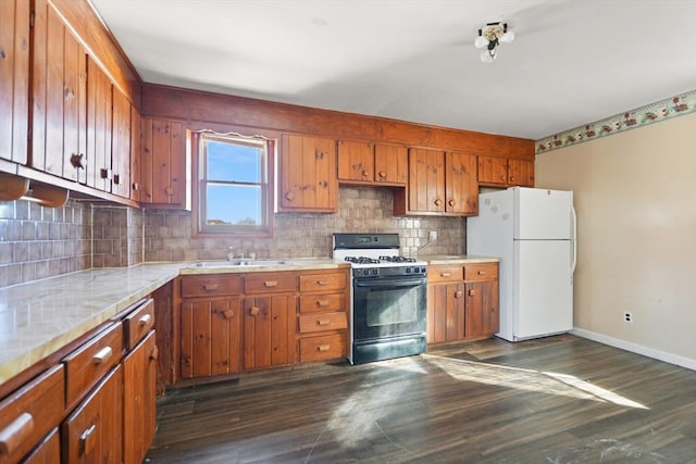 kitchen with dark wood-type flooring, sink, white refrigerator, gas range oven, and decorative backsplash