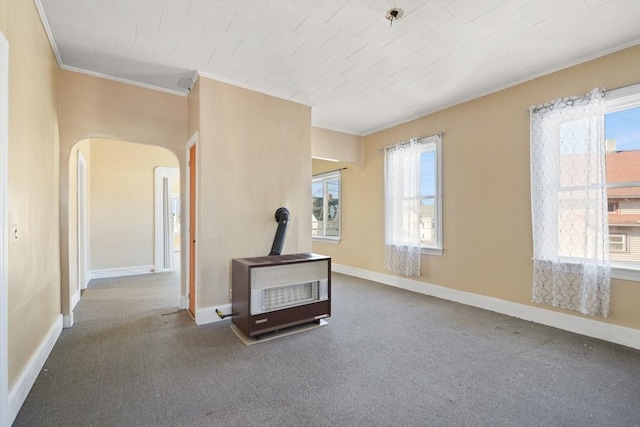 unfurnished living room with crown molding, a wealth of natural light, and a wood stove