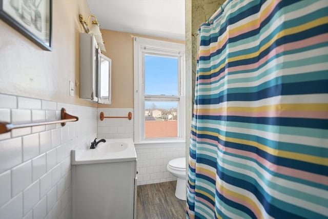 bathroom featuring vanity, hardwood / wood-style flooring, tile walls, and toilet