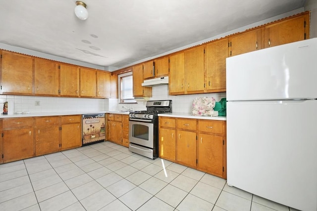 kitchen featuring light tile patterned flooring, tasteful backsplash, dishwasher, white fridge, and stainless steel gas range