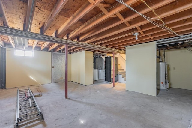 basement featuring stairs, water heater, and washer and clothes dryer