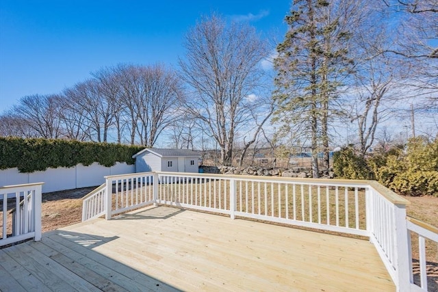 wooden deck featuring a storage shed, an outbuilding, and fence