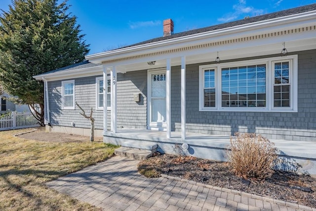 view of front of property featuring a porch, a chimney, and fence