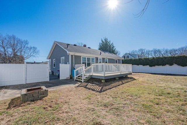 rear view of property with a deck, a fenced backyard, and a lawn