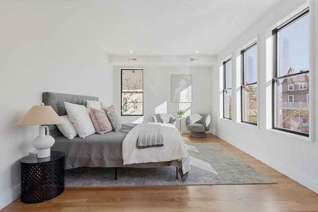 bedroom with wood finished floors, visible vents, and baseboards