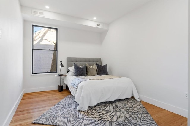 bedroom featuring baseboards, visible vents, and wood finished floors