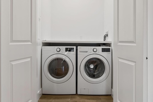 clothes washing area with laundry area, washing machine and dryer, and wood tiled floor