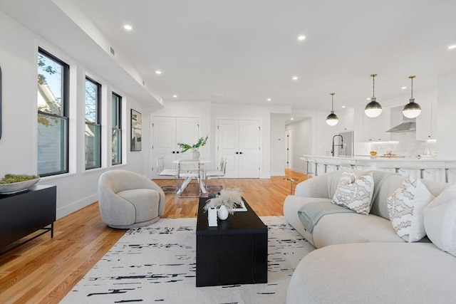 living room with baseboards, recessed lighting, visible vents, and light wood-style floors