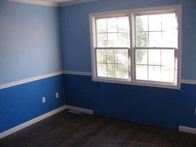 unfurnished room featuring crown molding and dark wood-type flooring