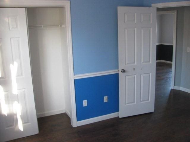 unfurnished bedroom featuring a closet and dark wood-type flooring