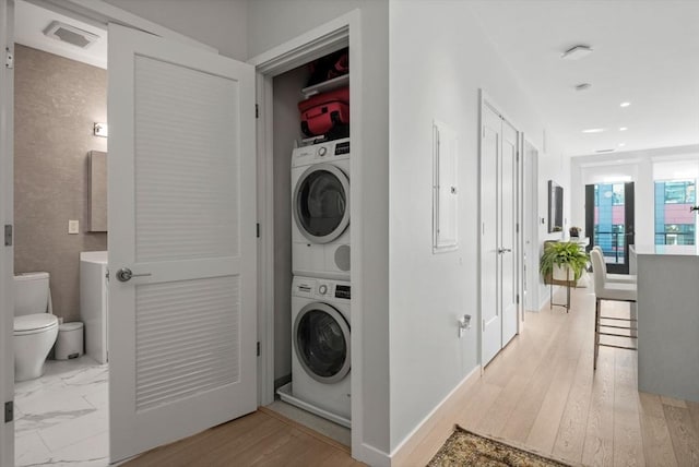 laundry room featuring electric panel and stacked washer and clothes dryer