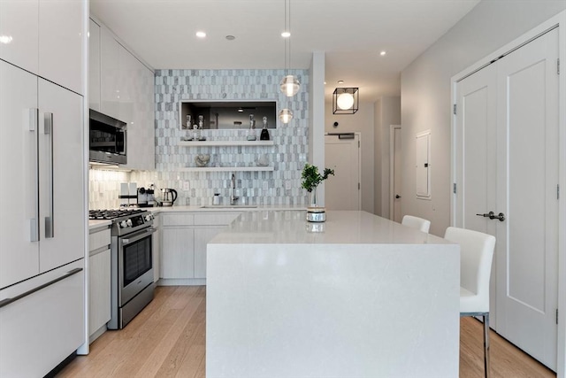 kitchen featuring white cabinets, sink, hanging light fixtures, built in appliances, and tasteful backsplash