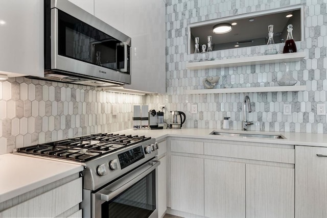 kitchen featuring white cabinets, backsplash, sink, and appliances with stainless steel finishes