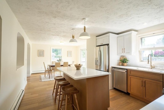 67 Paris Ave, Worcester, MA 01603 - kitchen featuring appliances with stainless steel finishes, a sink, baseboard heating, arched walkways, and light wood finished floors