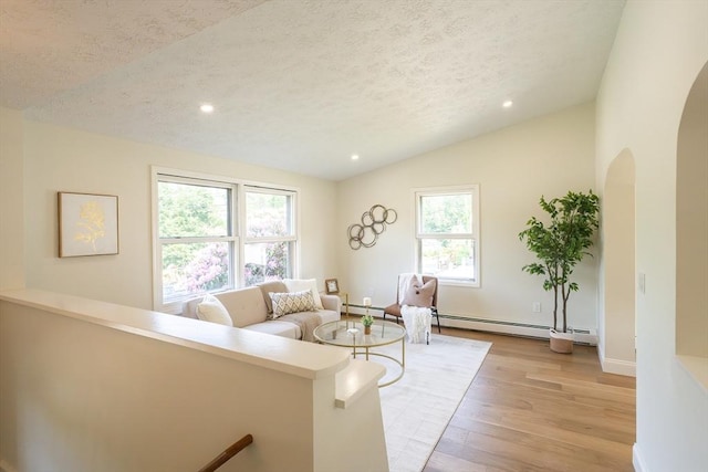 67 Paris Ave, Worcester, MA 01603 - living room featuring a textured ceiling, lofted ceiling, light wood finished floors, a baseboard radiator, and arched walkways