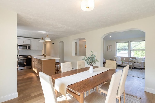 67 Paris Ave, Worcester, MA 01603 - dining space with arched walkways, dark wood-style floors, baseboards, and a textured ceiling