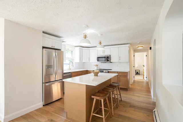 67 Paris Ave, Worcester, MA 01603 - kitchen featuring stainless steel appliances, light wood finished floors, a textured ceiling, a kitchen island, and a breakfast bar