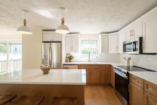 67 Paris Ave, Worcester, MA 01603 - kitchen with appliances with stainless steel finishes, a sink, light wood finished floors, light countertops, and a textured ceiling