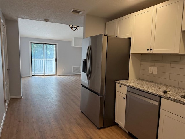 100 Cass Ave Unit B20, Dracut, MA 01826 - kitchen featuring stainless steel appliances, tasteful backsplash, open floor plan, white cabinets, and light wood finished floors