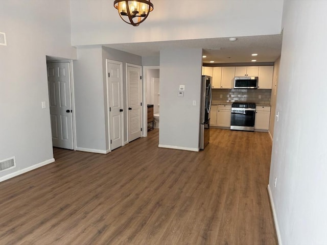 100 Cass Ave Unit B20, Dracut, MA 01826 - kitchen with appliances with stainless steel finishes, open floor plan, white cabinets, dark wood-type flooring, and tasteful backsplash