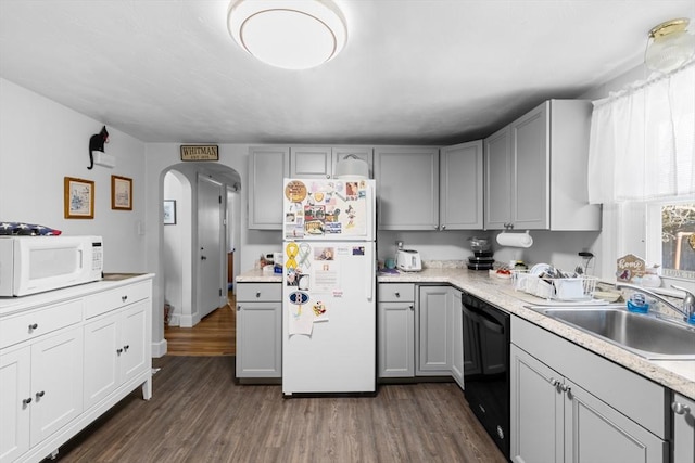 kitchen with white appliances, dark wood-style floors, gray cabinets, arched walkways, and a sink