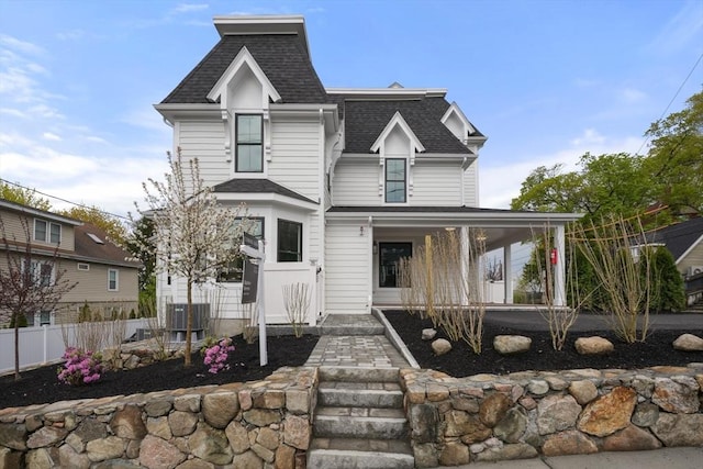 view of front of property featuring a porch, a shingled roof, fence, and central air condition unit