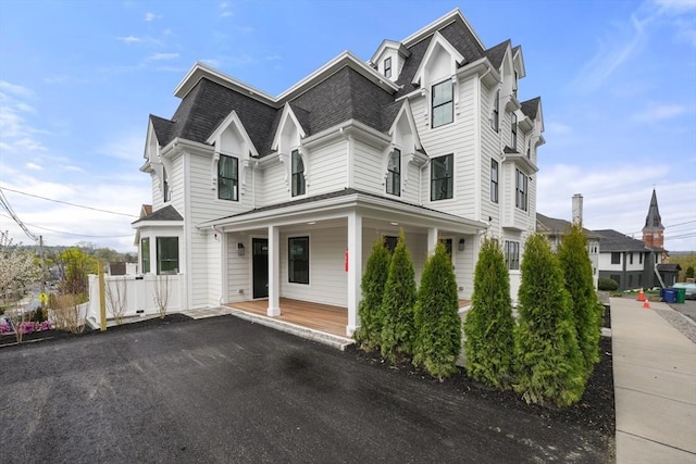 victorian home with a porch and roof with shingles