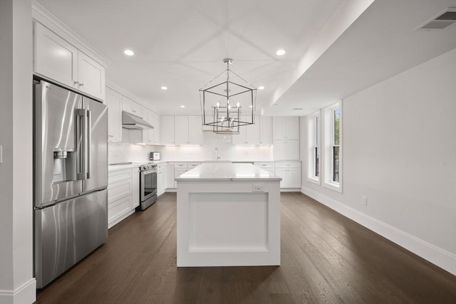 kitchen featuring light countertops, baseboards, under cabinet range hood, stainless steel appliances, and white cabinetry
