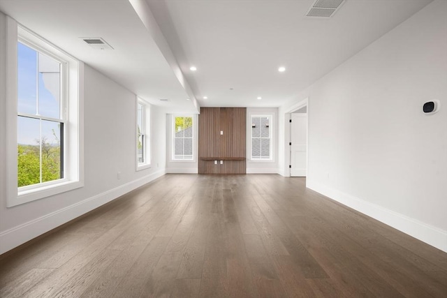 unfurnished living room with baseboards, dark wood-style floors, and visible vents