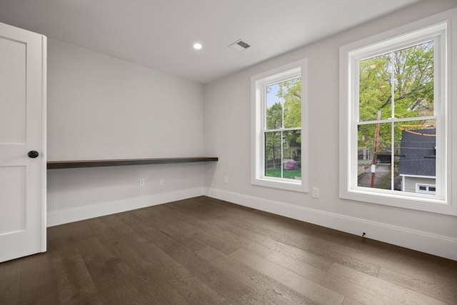 spare room featuring dark wood-style flooring, baseboards, visible vents, and recessed lighting