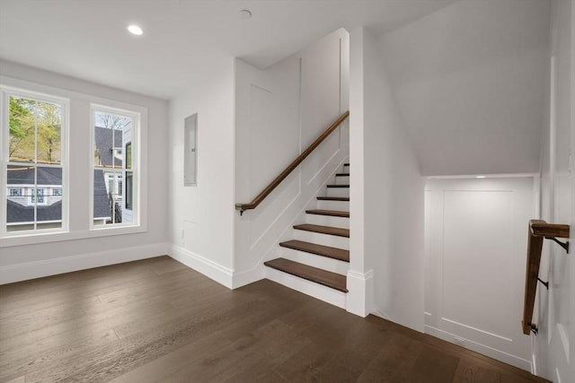 staircase with baseboards, electric panel, recessed lighting, and wood finished floors