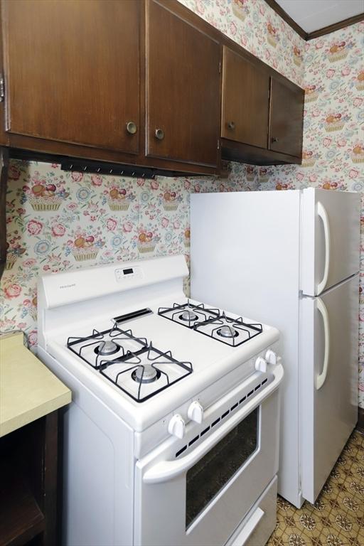 kitchen featuring dark brown cabinetry and white gas range oven