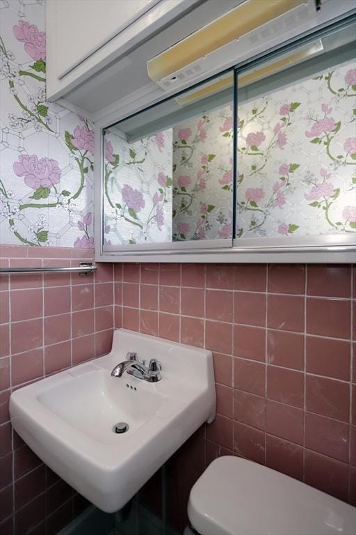 bathroom featuring sink, tile walls, and toilet