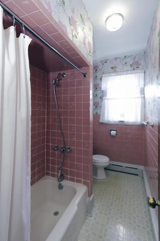 bathroom with baseboard heating, toilet, and shower / bath combo with shower curtain