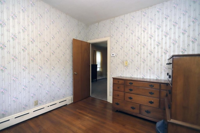 unfurnished bedroom with a baseboard heating unit and dark hardwood / wood-style flooring