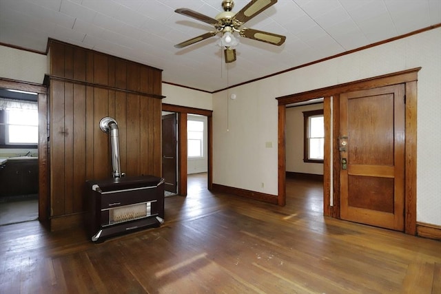 living room featuring dark wood-type flooring, plenty of natural light, ceiling fan, and a wood stove