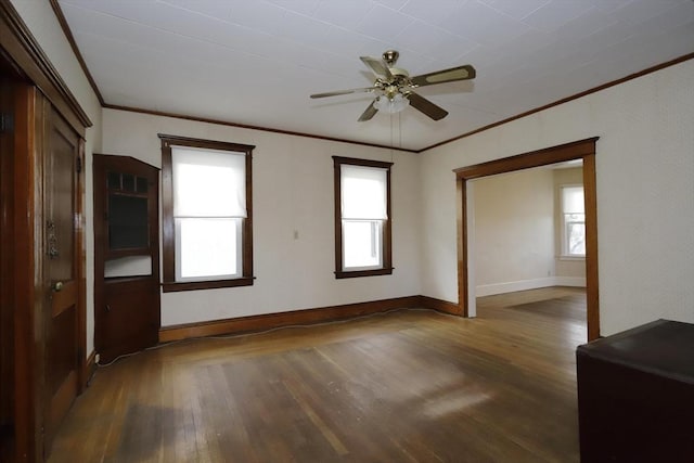 empty room with a healthy amount of sunlight, dark wood-type flooring, and ceiling fan