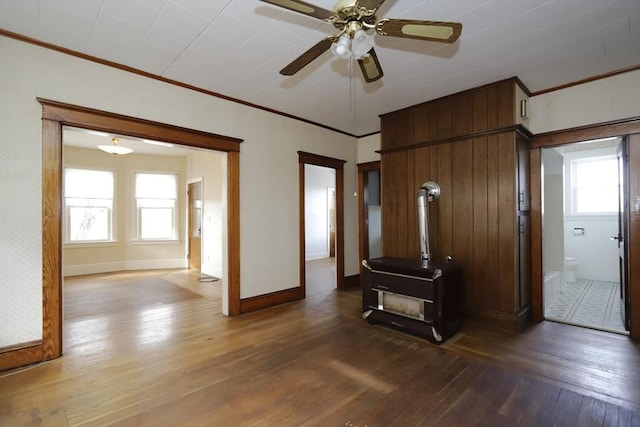 unfurnished living room featuring hardwood / wood-style floors, plenty of natural light, ceiling fan, and a wood stove